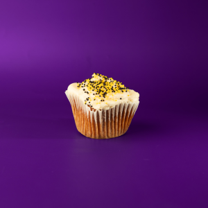 A honey cupcake topped with honey cream cheese and finished with black and yellow nonpareils. Honey cupcake