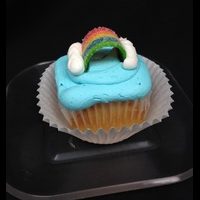 A vanilla cupcake with a Skittles candy filling, topped with blue vanilla buttercream, and finished with vanilla buttercream clouds and a rainbow candy piece. End of the Rainbow cupcake