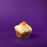 A carrot cupcake with cream cheese icing and a buttercream carrot. Carrot cupcake