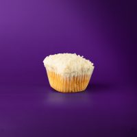 A coconut cupcake with cream cheese icing and coconut flakes on top. Coconut cupcake