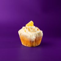 A pineapple cupcake filled with coconut pudding, topped with cream cheese icing and finished with toasted coconut and a dried pineapple tidbit. Pina Colada cupcake