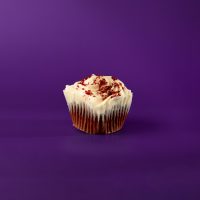 A red velvet cupcake with cream cheese icing topped with red velvet crumbles. Red Velvet cupcake