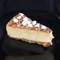A white chocolate cheesecake topped with ganache and white morsels. White Chocolate