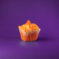 An orange cupcake topped with orange cream cheese icing and finished with an orange candy wedge. Orange Creamsicle cupcake
