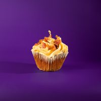 A brown sugar bacon cupcake topped with brown sugar cream cheese icing and bacon pieces. Brown Sugar Bacon cupcake