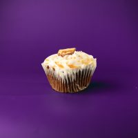 A chocolate cupcake with peanut butter chips, topped with vanilla buttercream and finished with a piece of a Snickers candy bar. Snickers cupcake