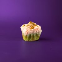 A cherry pistachio cupcake filled with pistachio pudding, covered in cherry cream cheese icing and topped with crushed pistachios. Cherry Pistachio cupcake
