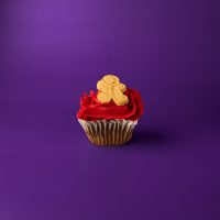 A gingerbread cupcake topped with red gingerbread cream cheese icing and finished with a mini gingerbread man cookie. Gingerbread cupcake