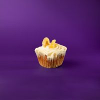 A banana, pineapple and pecan cupcake topped with cream cheese icing and finished with a banana chip and a dried pineapple tidbit. Hummingbird cupcake