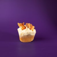A cinnamon cupcake with bacon pieces, brown sugar cream cheese icing, and cinnamon sugar, topped with bacon pieces, and finished with a maple syrup drizzle. French Toast cupcake