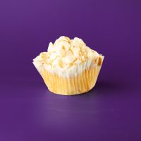 A vanilla cupcake filled with peanut butter ganache, iced with vanilla buttercream and topped with white morsels and peanut butter drizzle. White Chocolate Peanut Butter cupcake