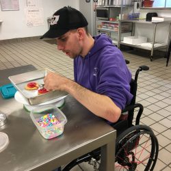 A staff member decorating a sugar cookie